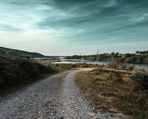 Person doing light jogging on a gravel path near a river